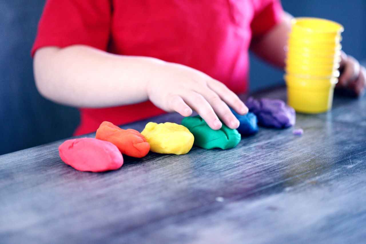 Crafting Captivating Headlines: Your awesome post title goes here A young child with rainbow-colored modeling clay and stacking cups on a table indoors.