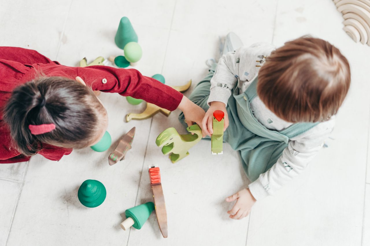 Two young children playing with colorful wooden toys indoors, promoting creativity and fun.