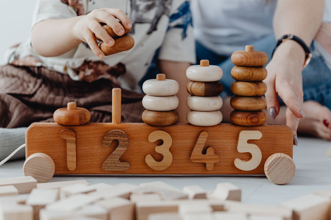 about-us-01 A child and adult playing with wooden number toys, enhancing learning and coordination skills.