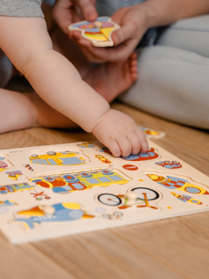 services-02 Close-up of a baby engaged with a colorful educational puzzle indoors.